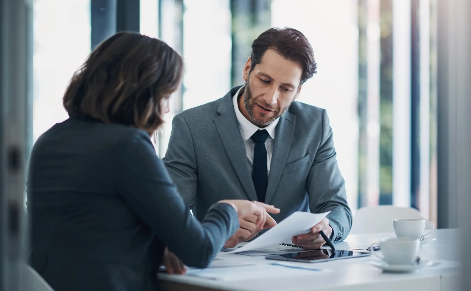 Two legal professionals carefully reviewing and marking a business contract