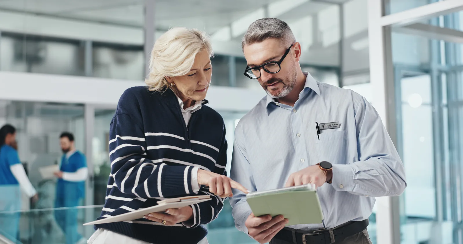 Healthcare and legal professionals reviewing compliance requirements together on a tablet